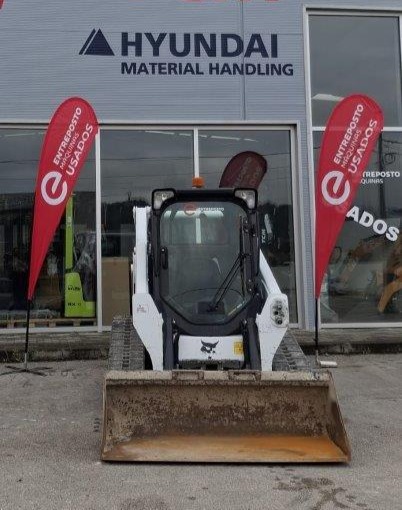 Mini carregador Bobcat T590 usado, estacionado à frente do stand Entreposto Máquinas, especialista em equipamentos usados de construção e movimentação de materiais